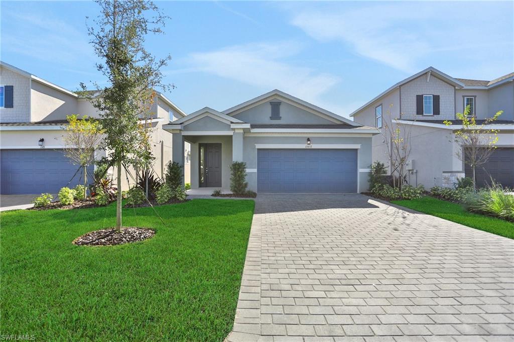 View of front of home featuring decorative driveway, stucco siding, a front lawn, and an attached garage