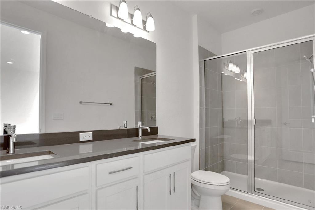 Full bathroom with double vanity, a stall shower, and light tile patterned floors