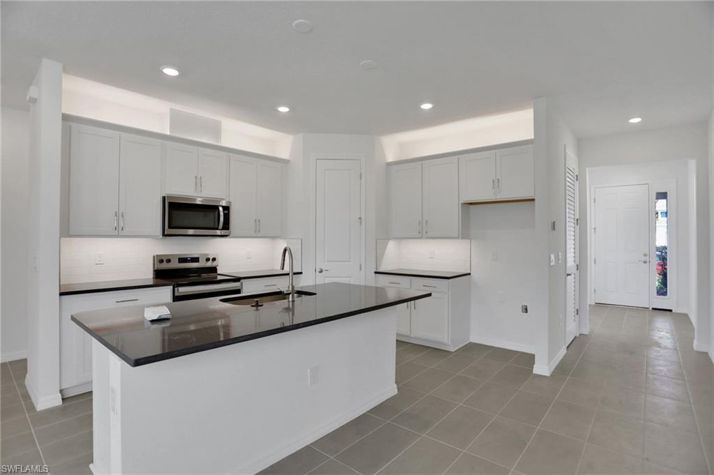 Kitchen featuring stainless steel appliances, an island with sink, recessed lighting, white cabinets, and light tile patterned flooring