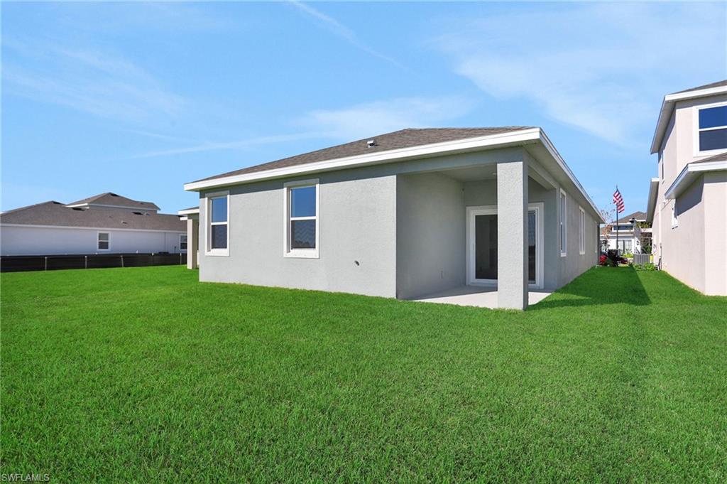 Back of house with stucco siding, a patio area, and a shingled roof
