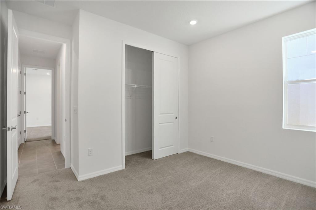 Unfurnished bedroom featuring light carpet, a closet, and recessed lighting