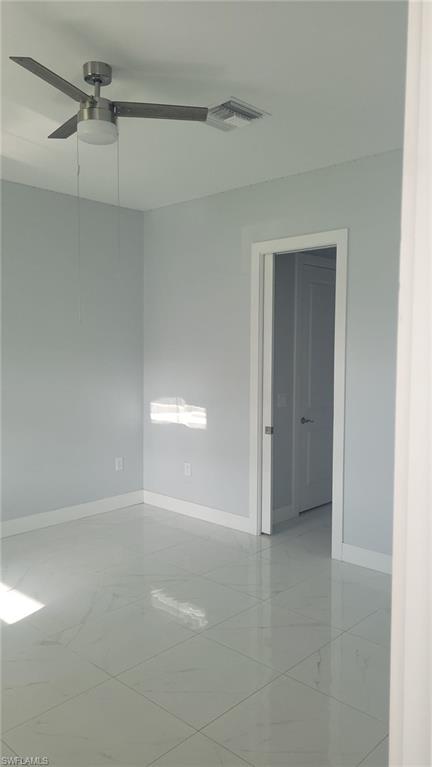 Contemporary interior space featuring light-toned walls, white baseboards, and large format polished tile flooring
