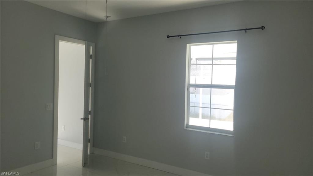 Bright interior room featuring a large window with horizontal and vertical mullions, a dark-toned curtain rod, and light gray wall paint