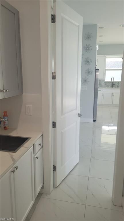 White paneled interior door opening to a space featuring large format white tile flooring with subtle veining