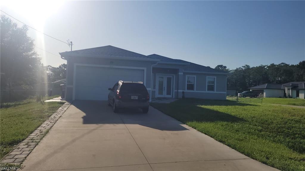 Contemporary single-story residence featuring a light blue exterior, attached two-car garage, and a concrete driveway with paver edging