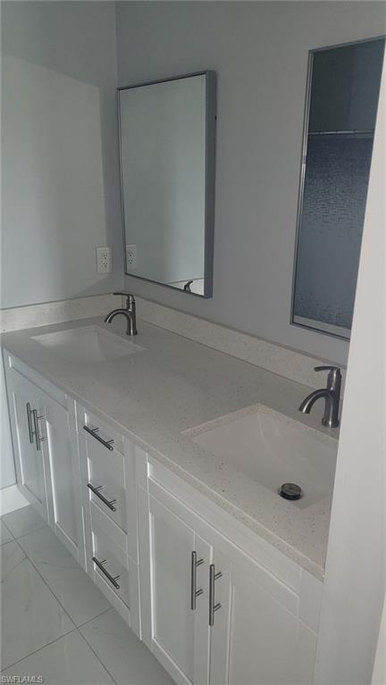 White shaker cabinetry with brushed nickel hardware, dual undermount sinks, and a light-toned countertop