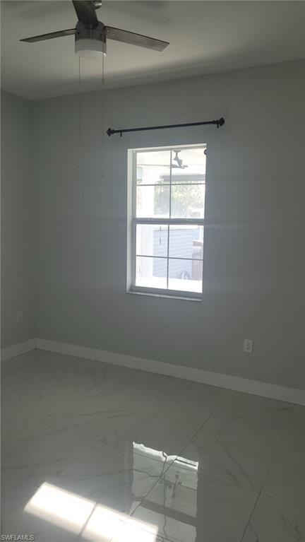 Bright room featuring a window with a curtain rod, a ceiling fan with integrated lighting, and large format polished tile flooring