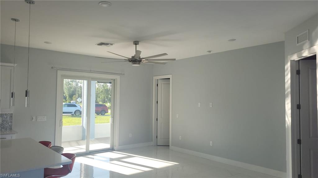 Open living space featuring large sliding glass doors, a modern ceiling fan, recessed lighting, and light-toned tile flooring