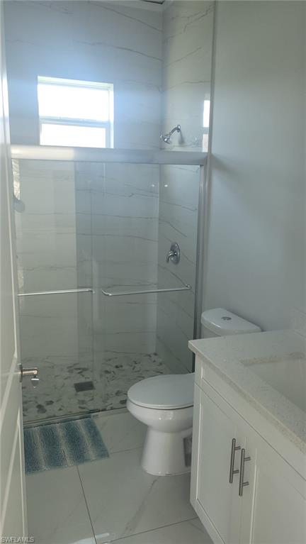 Contemporary bathroom featuring a frameless glass shower enclosure with white tiled walls and a mosaic floor
