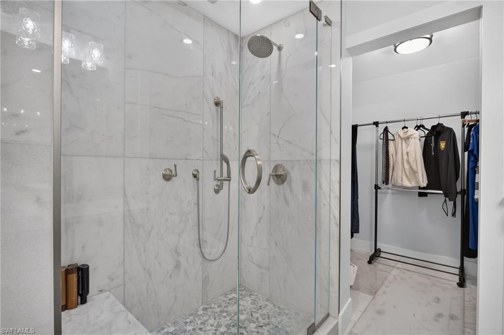 Shower with Custom tiled shower, glass shower door, and multiple heads.