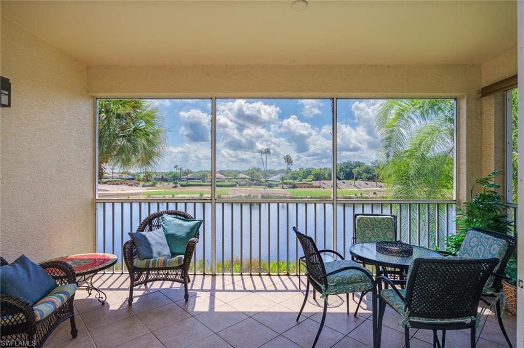Screened lanai featuring tile flooring, a textured ceiling, exterior wall sconce, and a water-body backdrop with distant green spaces