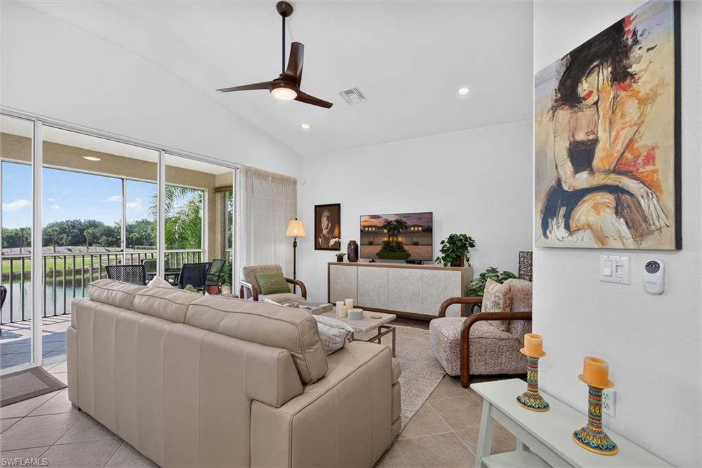 Living space featuring large sliding glass doors, vaulted ceilings, recessed lighting, and a ceiling fan