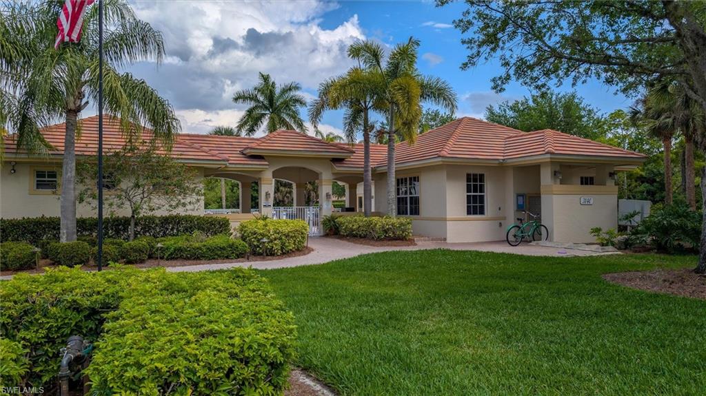 Tile roof structure with arched entryway, perimeter landscaping, and mature palm trees