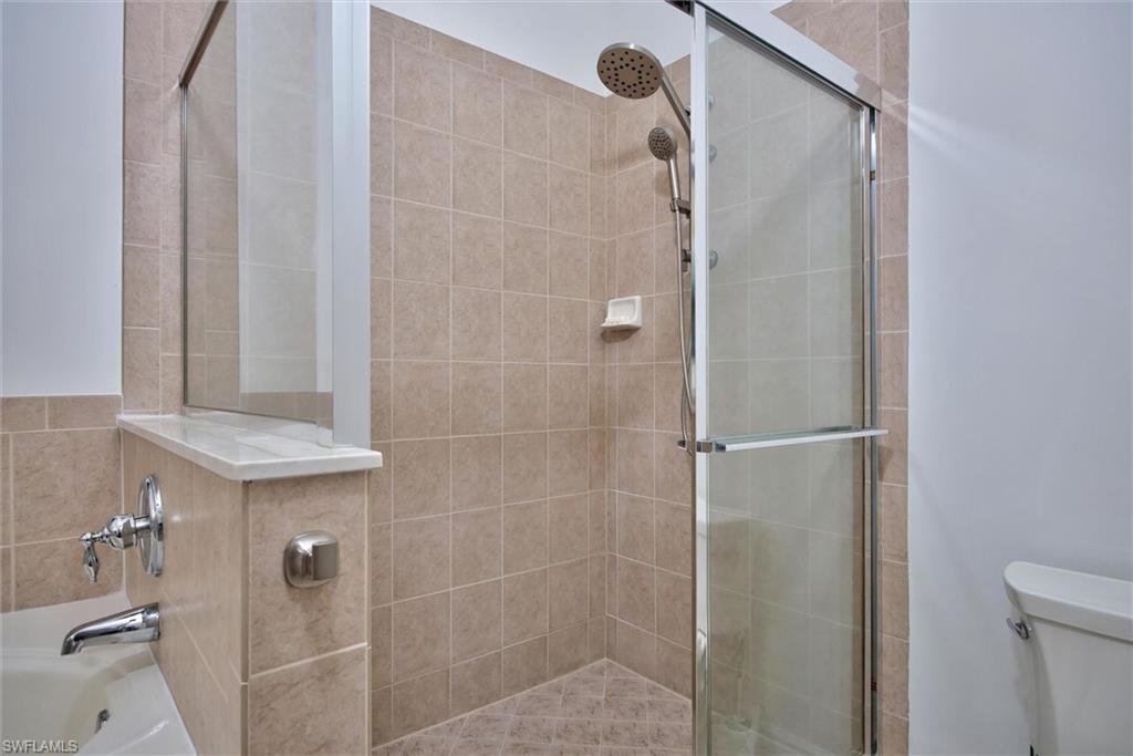 Shower with a glass enclosure, a handheld showerhead, and a fixed showerhead