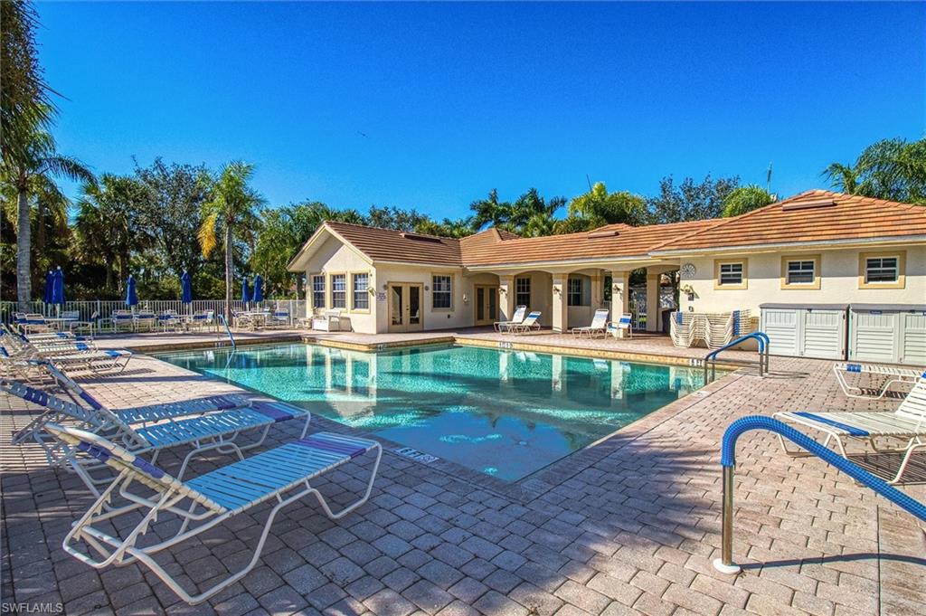 Expansive swimming pool area featuring a paver deck, multiple lounge chairs, and an adjacent structure with a barrel tile roof
