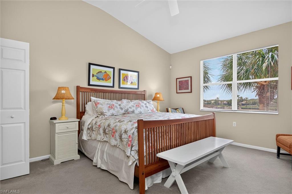 Spacious room featuring vaulted ceilings, a large window with white blinds, and light gray carpeting