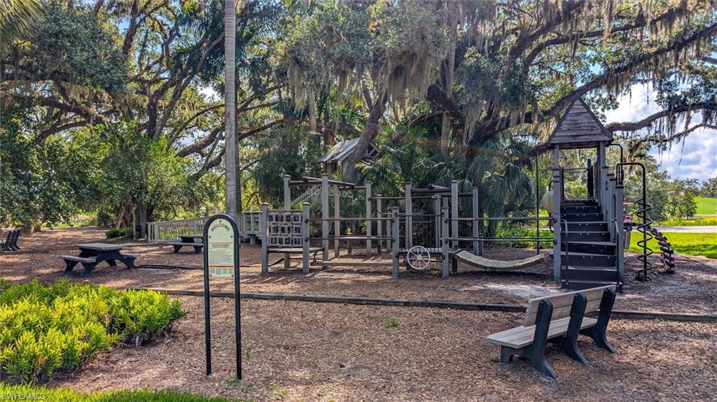 Wood-finish playground structure featuring multiple platforms, stairs, and a spiral slide