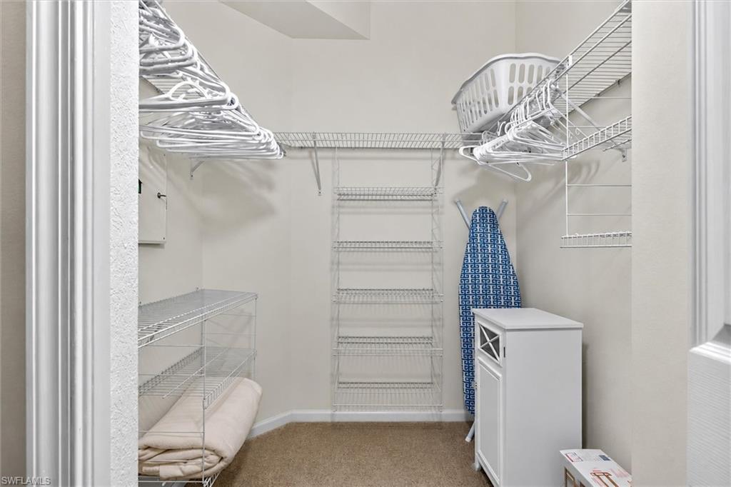 Organized closet space featuring wire shelving systems, multiple hanging rods, and neutral carpet flooring