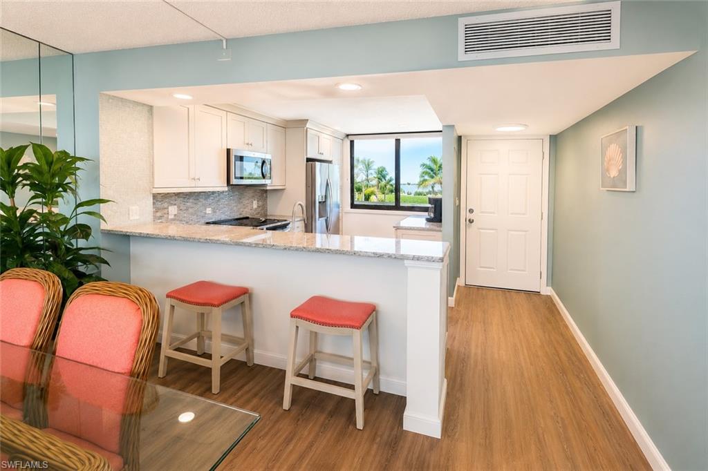 Kitchen featuring white cabinetry, stainless steel appliances, granite countertops, and a full-height tile backsplash