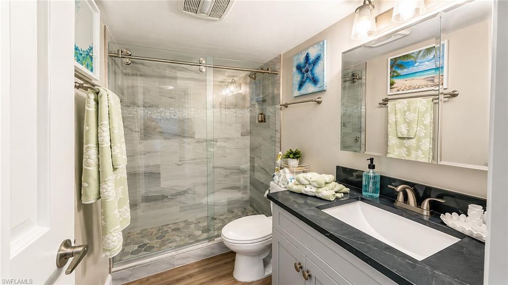 Bathroom featuring a glass-enclosed shower with pebble-finish flooring and tile walls