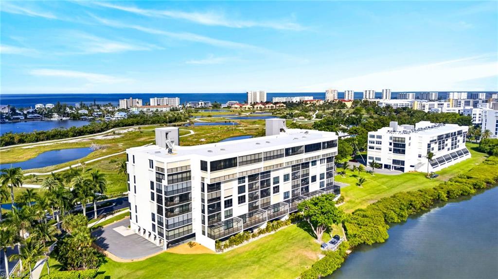 Contemporary multi-story building featuring expansive balconies, waterfront access, and surrounding green spaces