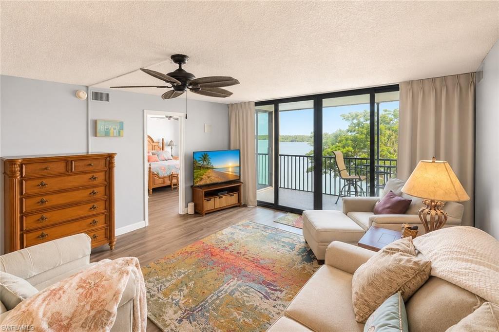 Living area with wood-finish flooring, ceiling fan, and access to a private balcony through sliding glass doors