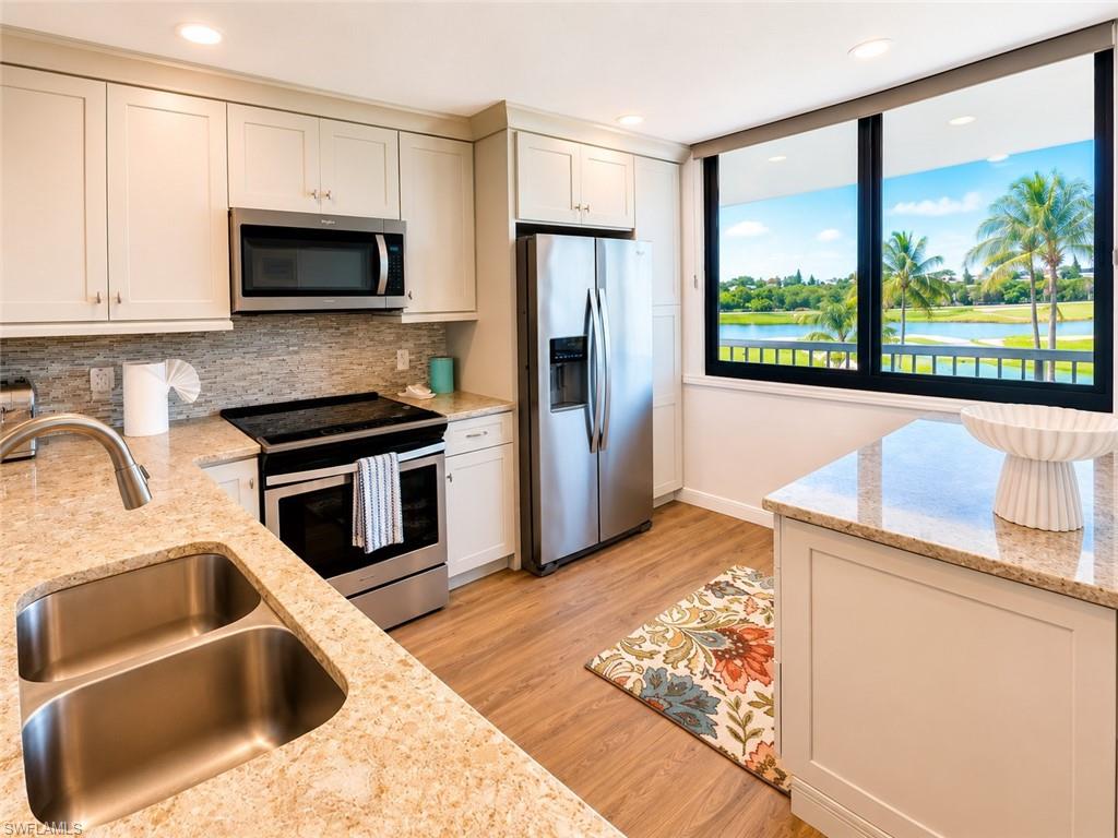 Kitchen featuring light-toned cabinetry, stainless steel appliances, and wood-finish flooring
