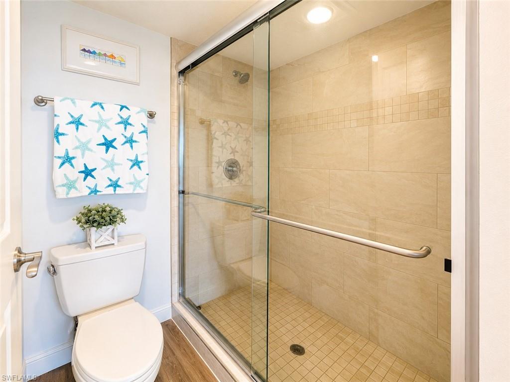 Glass-enclosed shower with full-height tile surround featuring a decorative mosaic accent band