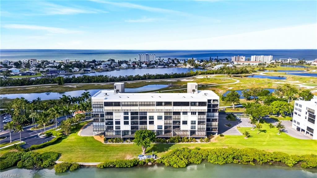 Waterfront condominium building featuring multiple levels of private balconies, manicured green spaces, and direct water access