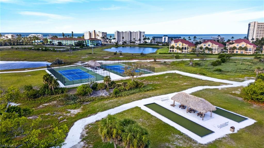 Multiple tennis courts, a thatched-roof pavilion with seating, and bocce ball courts surrounded by green spaces
