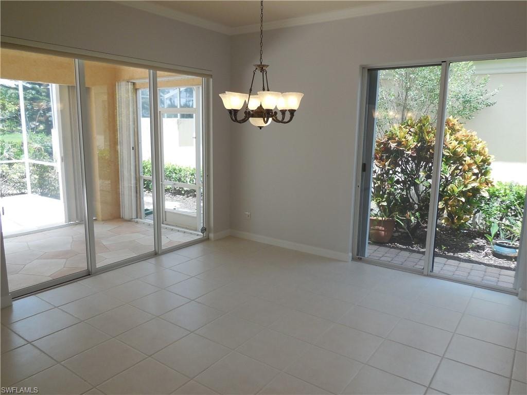 Interior space with light-toned ceramic tile flooring, crown molding, and a five-light chandelier