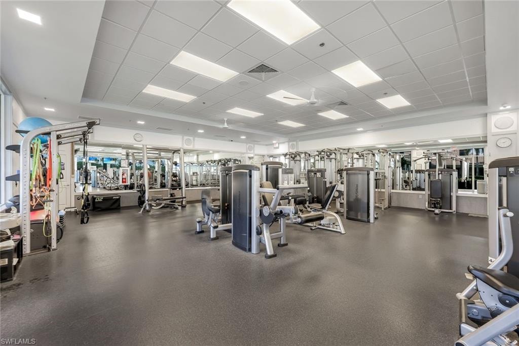 Fitness center featuring extensive mirrored walls, recessed lighting, and a durable rubberized floor