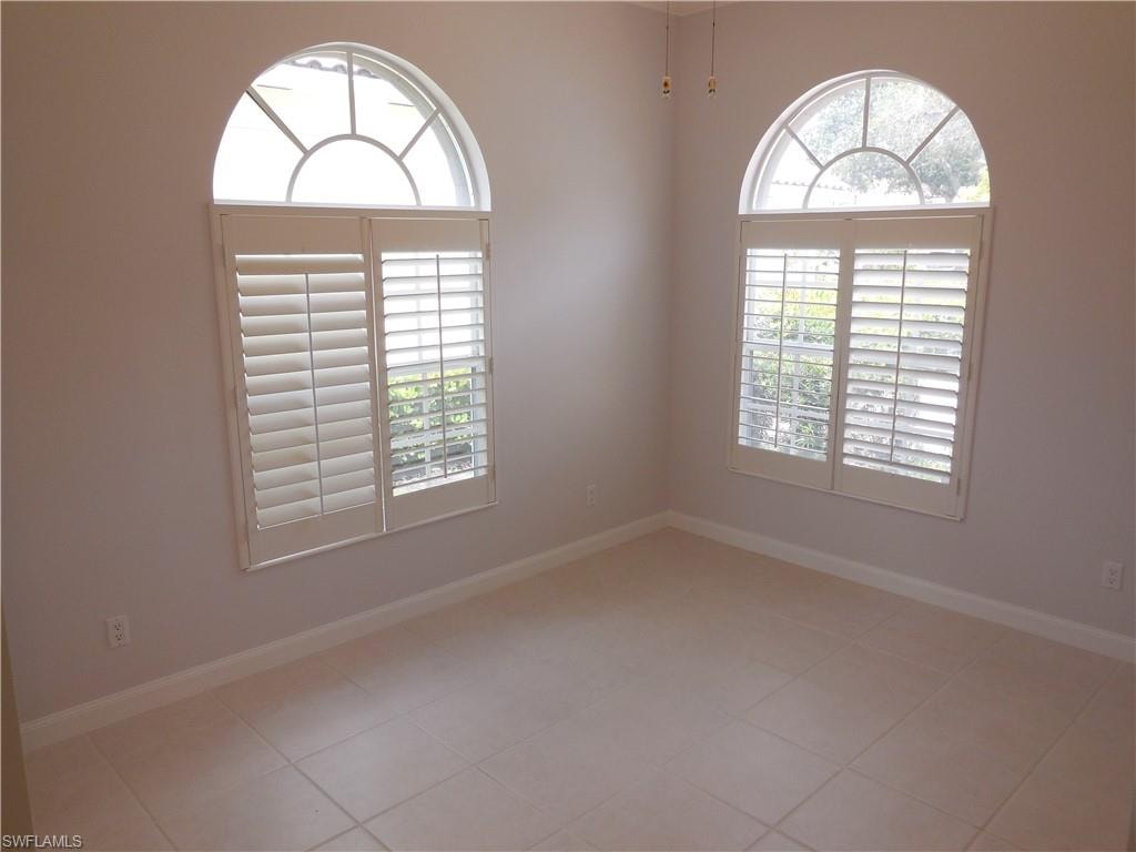 Room featuring two arched windows with decorative grilles and white louvered shutters
