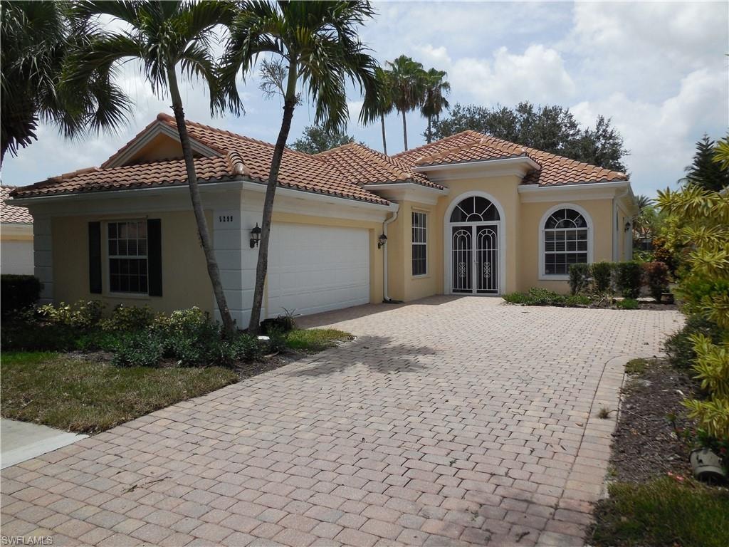 Mediterranean-inspired exterior with a distinctive tile roof and a paver driveway