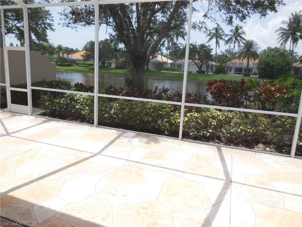 Screened outdoor living area featuring a light-toned flagstone-style patio, overlooking a tranquil body of water