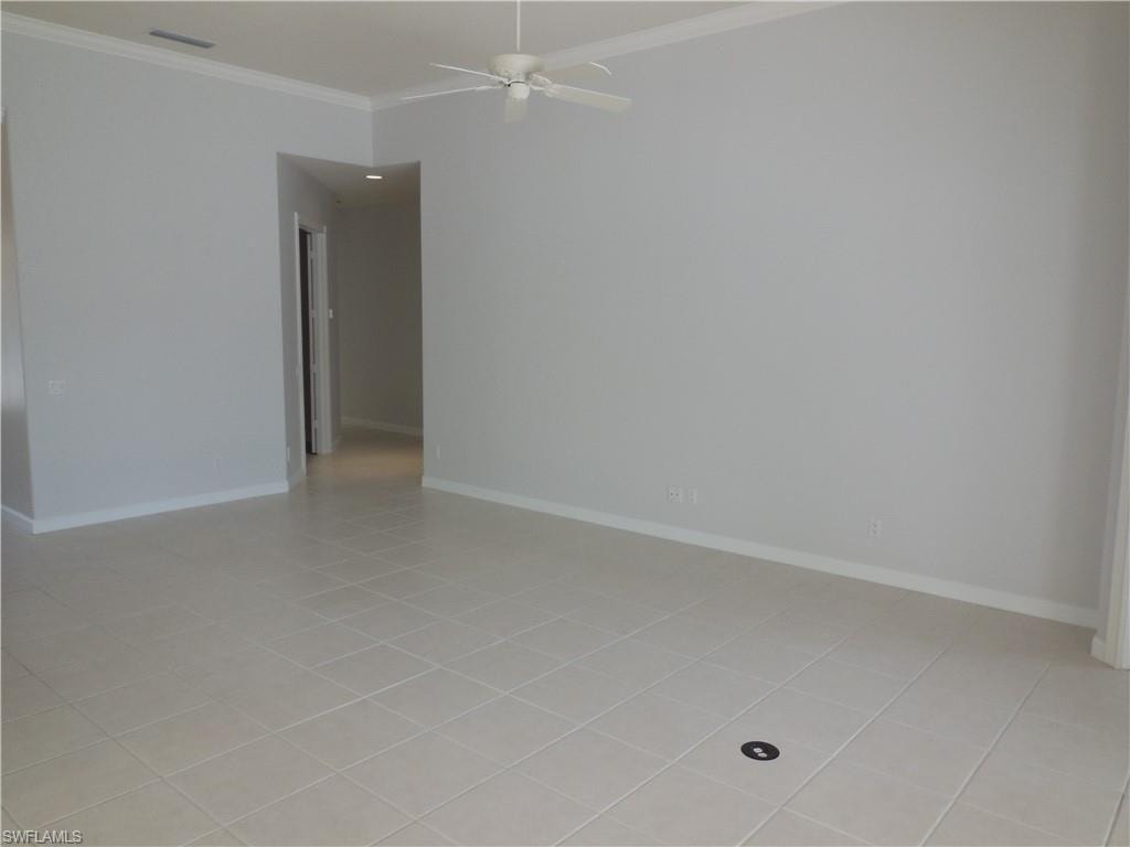 Spacious room featuring neutral-toned tile flooring, crown molding, and a ceiling fan