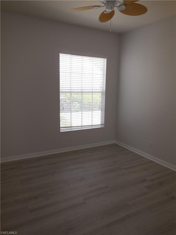 Room featuring a window with white blinds, wood-finish flooring, white baseboards, and a ceiling fan with woven blades
