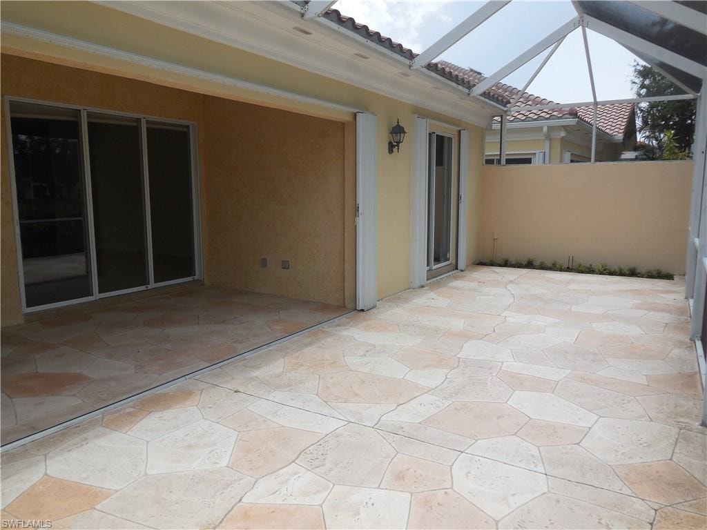 Expansive screened patio featuring large format irregular-shaped floor tiles, stucco exterior walls, and multiple sliding glass doors