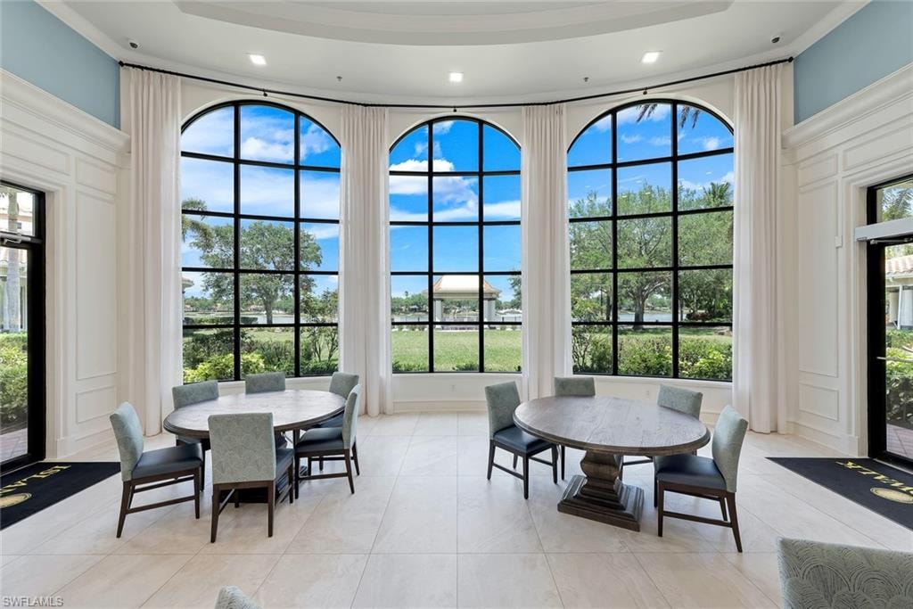 Grand arched windows with black mullions illuminate this space, showcasing a serene outdoor landscape