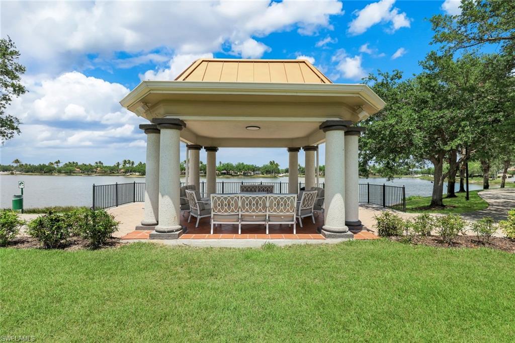 Lakeside gazebo featuring a beige metal roof, substantial columns, and a terracotta tile floor