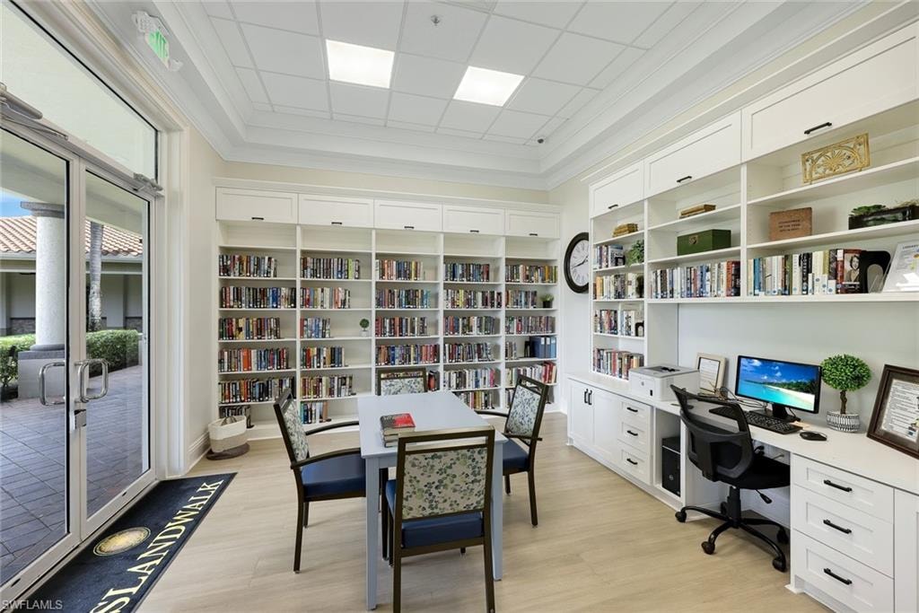 Library space featuring extensive built-in white shelving, wood-finish flooring, and crown molding