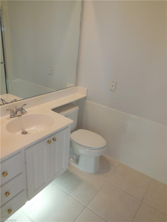Bathroom featuring a white vanity with gold-tone hardware, an integrated sink, and a large wall-mounted mirror