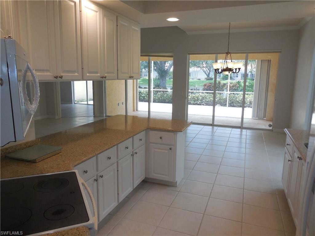 Kitchen featuring white cabinetry, light-toned countertops, and a mirrored backsplash