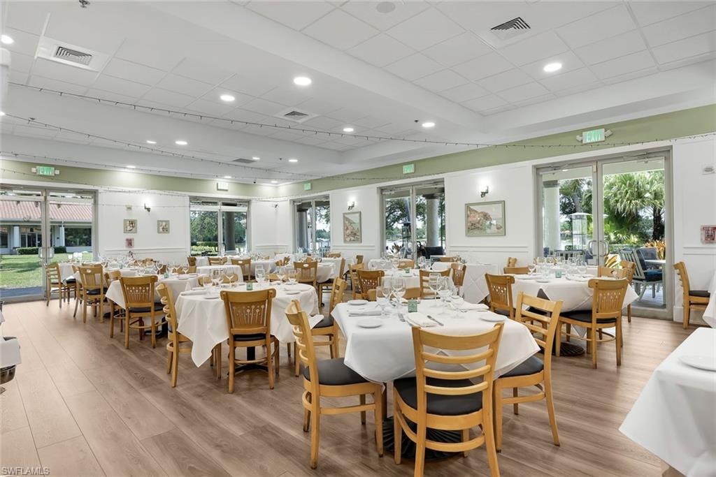 Spacious dining area featuring wood-finish flooring, recessed lighting, and multiple sliding glass doors providing access to outdoor areas