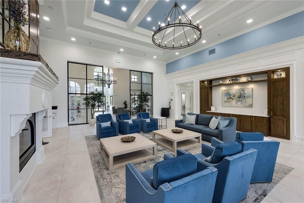 Spacious common area featuring a coffered ceiling, a large iron chandelier, built-in shelving, a fireplace, and large windowed partitions