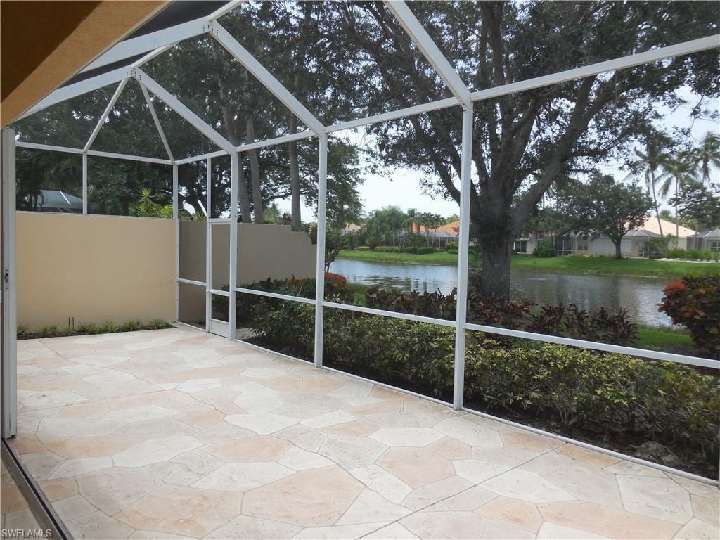 Screened patio featuring irregular-cut paver flooring, a vaulted ceiling, and a full-height privacy wall