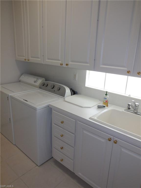 Functional laundry area featuring white cabinetry with gold-tone hardware