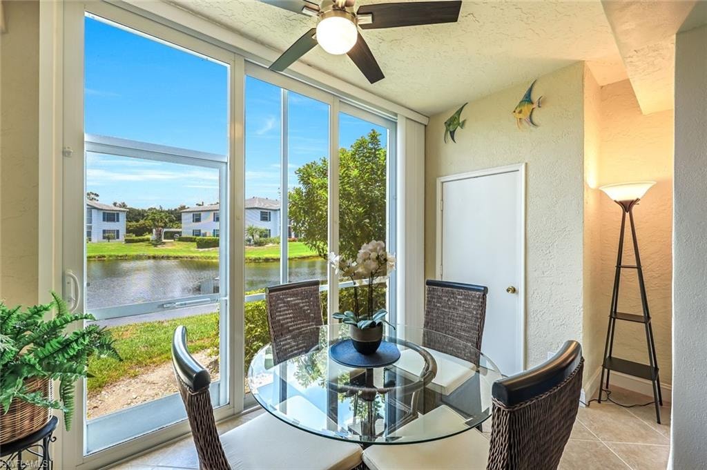 Sunroom with a water view and a ceiling fan
