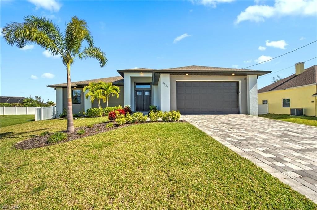 View of front of home with a front yard, a garage, and central AC