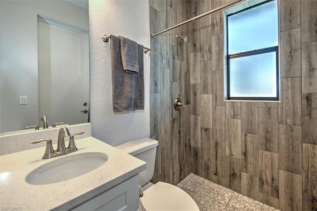 Bathroom with tiled shower, vanity, and toilet
